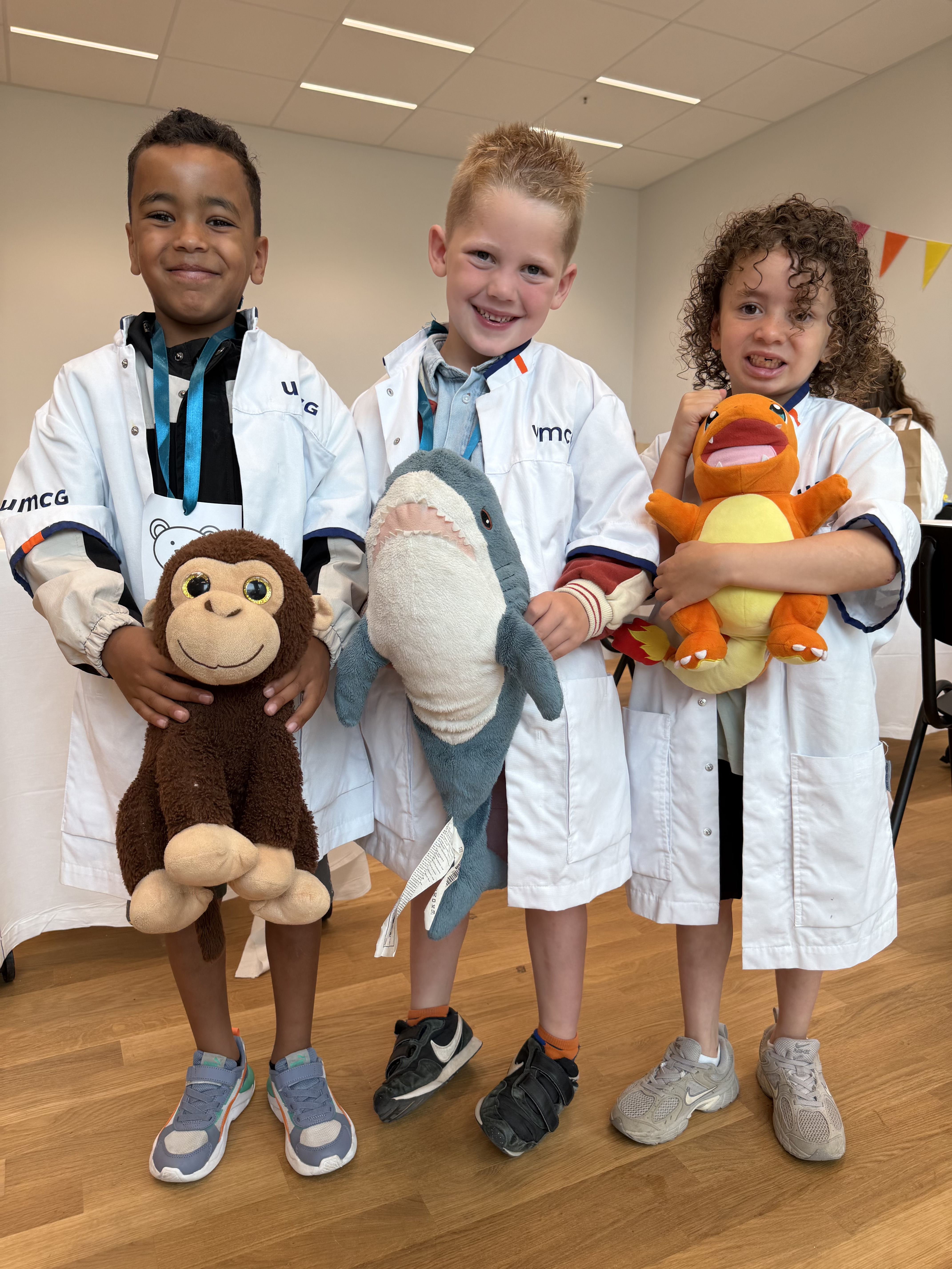Drie kleuters met een knuffeldier in hun handen bij Teddy Bear Hospital